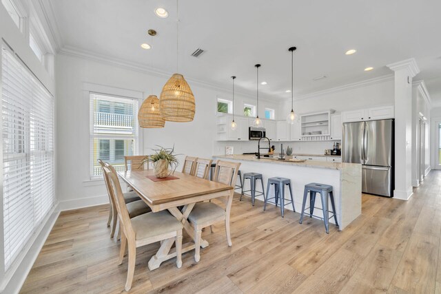 dining space with ornamental molding and light hardwood / wood-style floors