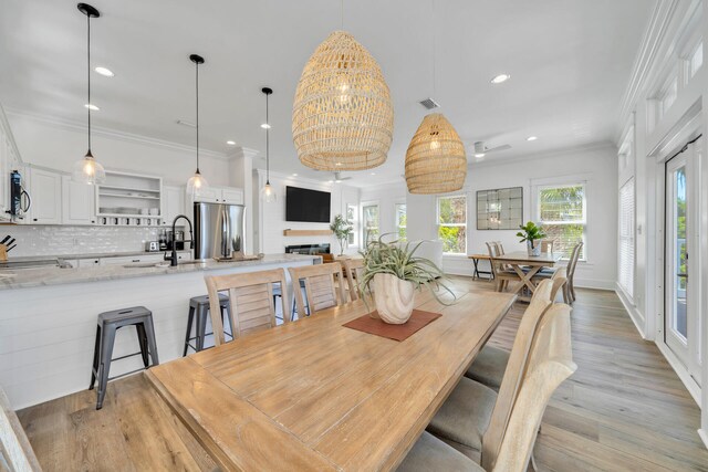 dining area featuring crown molding, light hardwood / wood-style flooring, an inviting chandelier, and sink