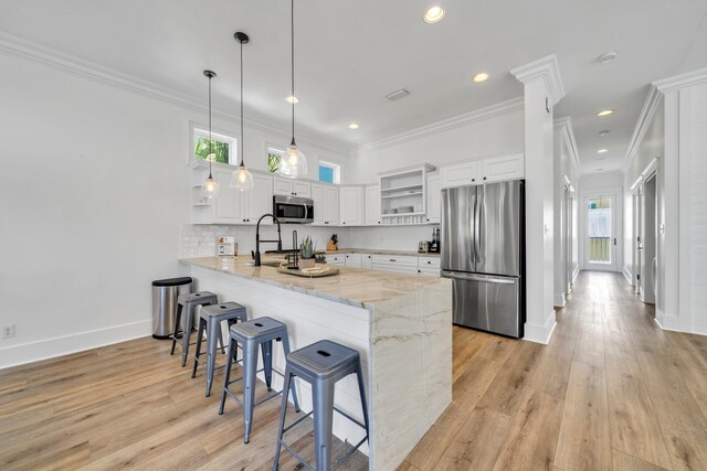 kitchen featuring stainless steel appliances, light stone counters, kitchen peninsula, and white cabinetry