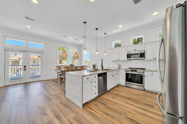 kitchen featuring kitchen peninsula, decorative light fixtures, appliances with stainless steel finishes, and white cabinets