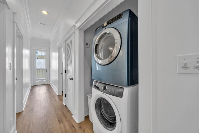 washroom with ornamental molding, light hardwood / wood-style flooring, and stacked washing maching and dryer