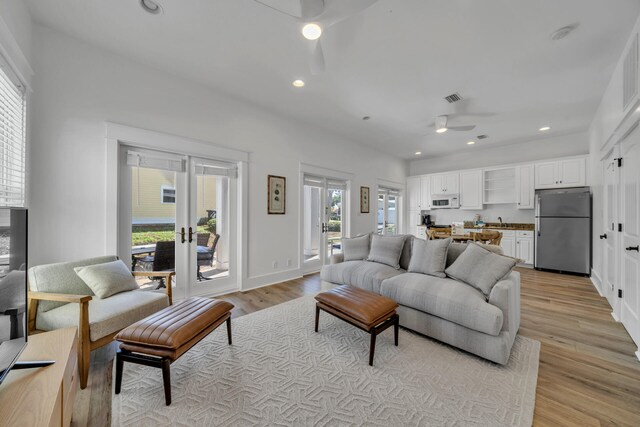 living room featuring ceiling fan, plenty of natural light, light hardwood / wood-style floors, and sink