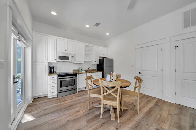 kitchen with plenty of natural light, stainless steel appliances, light hardwood / wood-style flooring, and white cabinetry