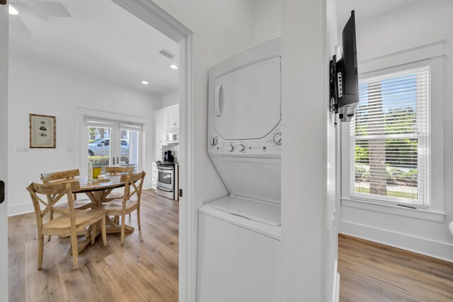 interior space with plenty of natural light, ceiling fan, stacked washer and dryer, and light hardwood / wood-style flooring