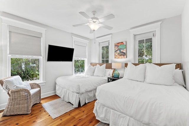 bedroom featuring ceiling fan, hardwood / wood-style flooring, and multiple windows