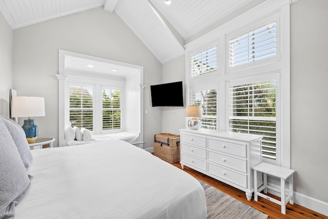 bedroom featuring hardwood / wood-style flooring and vaulted ceiling with beams