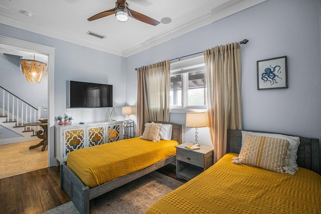 bedroom with dark wood-type flooring, ornamental molding, and ceiling fan with notable chandelier