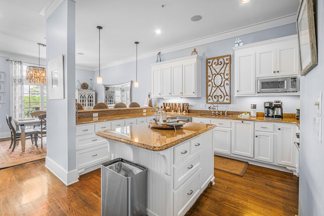 kitchen with hanging light fixtures, white cabinetry, kitchen peninsula, dark wood-type flooring, and stainless steel microwave