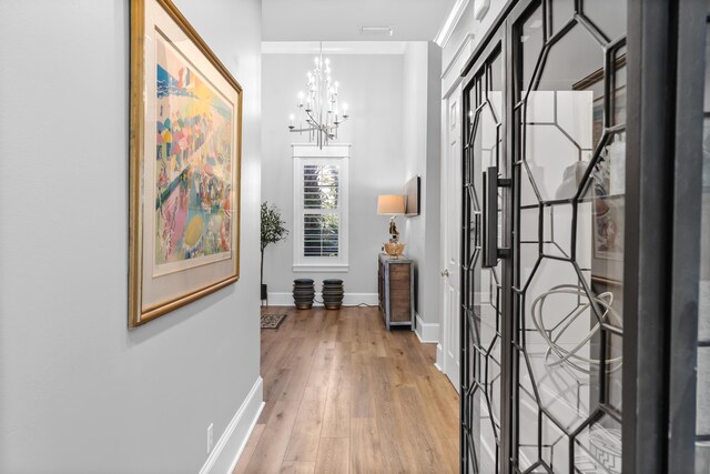 entrance foyer featuring ornamental molding, a notable chandelier, and hardwood / wood-style floors