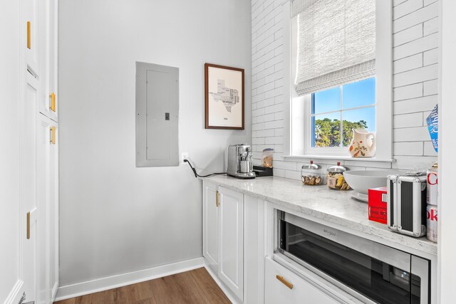 kitchen with white cabinetry, wine cooler, electric panel, light stone countertops, and dark hardwood / wood-style floors