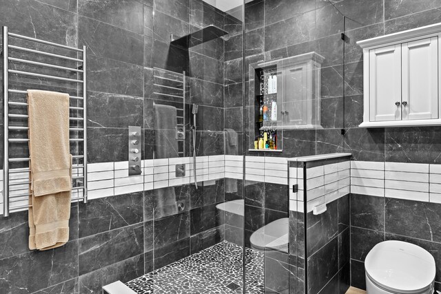 bathroom with tile walls, toilet, and a shower