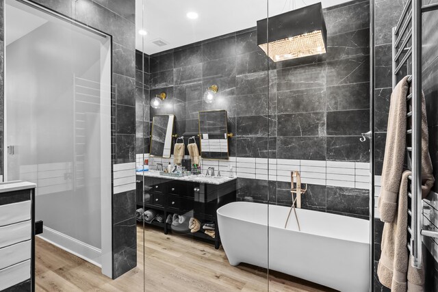 bathroom featuring vanity, tile walls, hardwood / wood-style floors, and a washtub