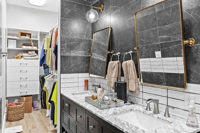 bathroom featuring double vanity, wood finished floors, backsplash, and a sink