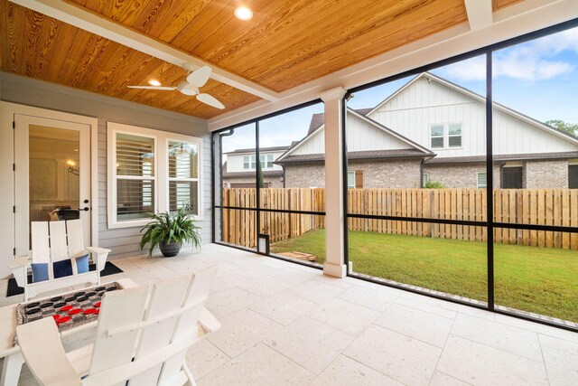 unfurnished sunroom featuring ceiling fan, wood ceiling, and plenty of natural light