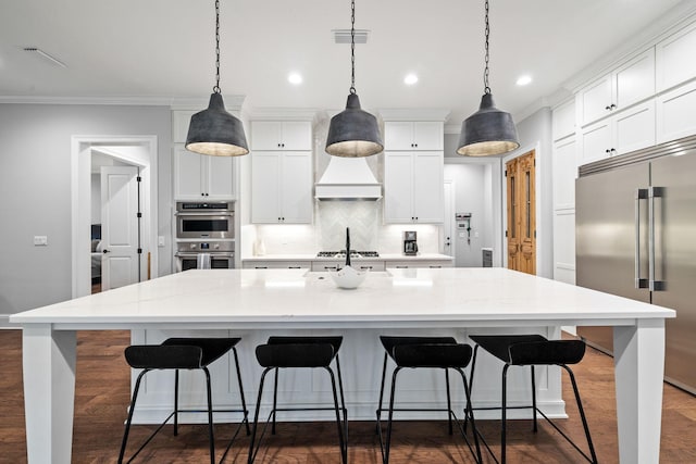 kitchen with a kitchen bar, pendant lighting, a large island with sink, and stainless steel appliances