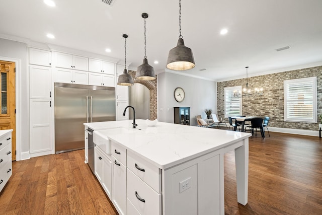 kitchen with an island with sink, white cabinetry, appliances with stainless steel finishes, and decorative light fixtures