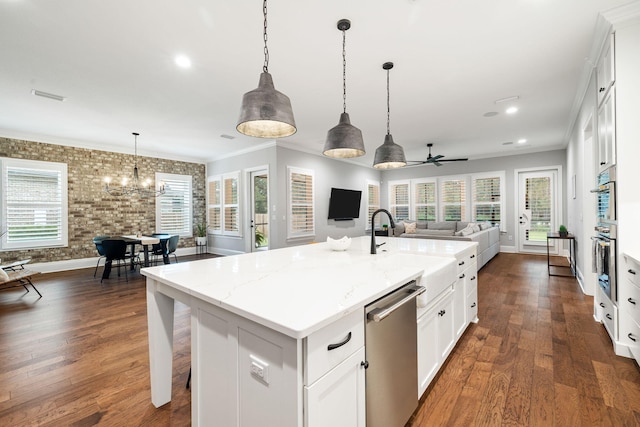 kitchen with an island with sink, white cabinetry, appliances with stainless steel finishes, and ceiling fan with notable chandelier