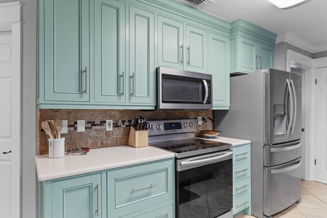 kitchen with green cabinetry, backsplash, stainless steel appliances, light tile patterned flooring, and ornamental molding