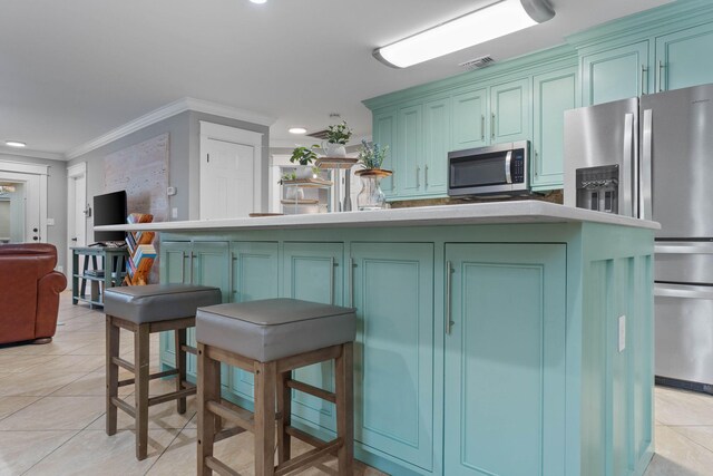 kitchen with crown molding, stainless steel appliances, green cabinetry, and light tile patterned floors