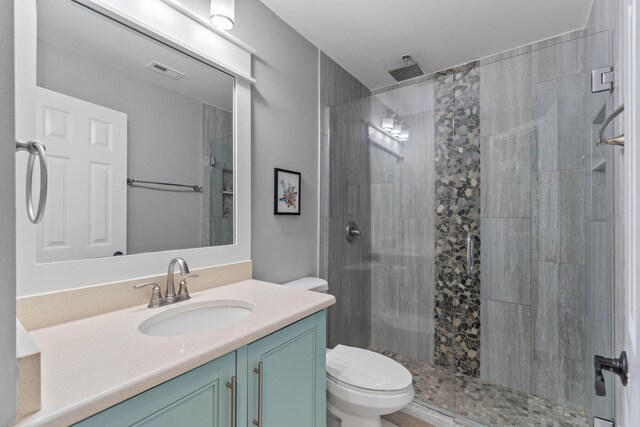 bathroom with a shower with door, vanity, and toilet