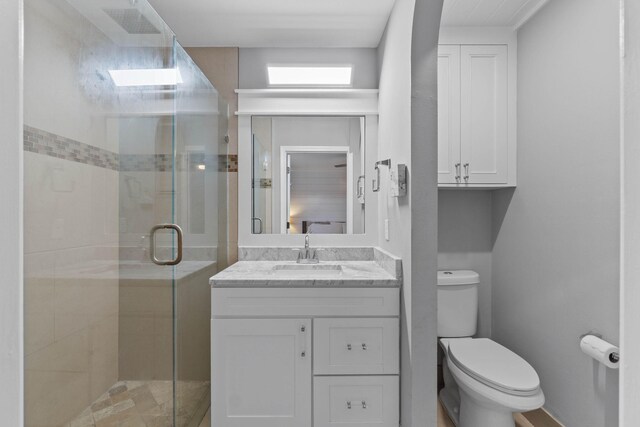 bathroom with vanity, toilet, and a shower with shower door