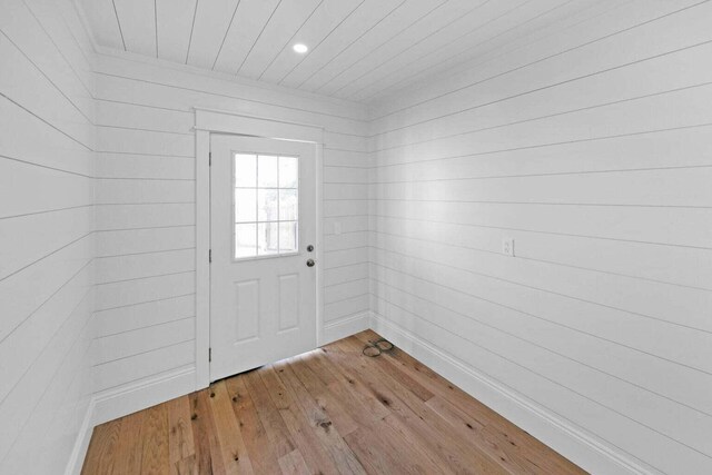 entryway with light hardwood / wood-style flooring and wood walls