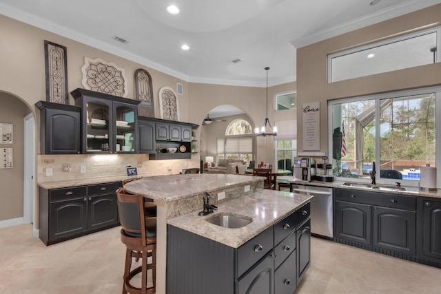 kitchen featuring an island with sink, stainless steel dishwasher, crown molding, and sink