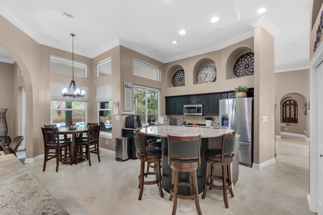 kitchen featuring light stone countertops, crown molding, a towering ceiling, and stainless steel appliances