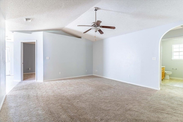 carpeted empty room with a textured ceiling, vaulted ceiling, and ceiling fan