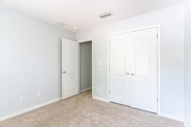 unfurnished bedroom featuring a closet, light colored carpet, and a textured ceiling