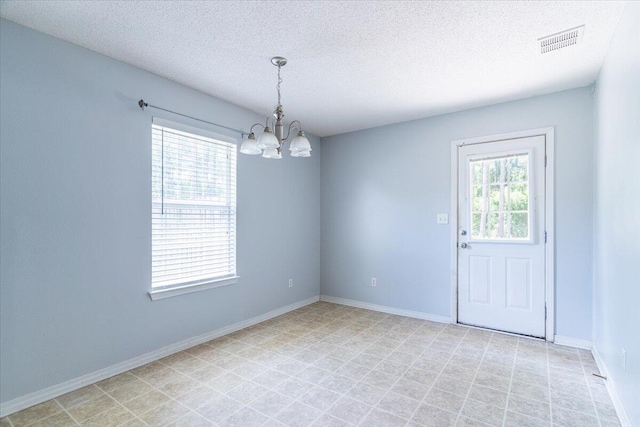 unfurnished room featuring a chandelier and a textured ceiling