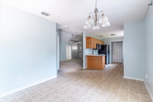 kitchen featuring stainless steel appliances, hanging light fixtures, and ceiling fan with notable chandelier