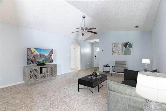 carpeted living room with a textured ceiling, vaulted ceiling, and ceiling fan