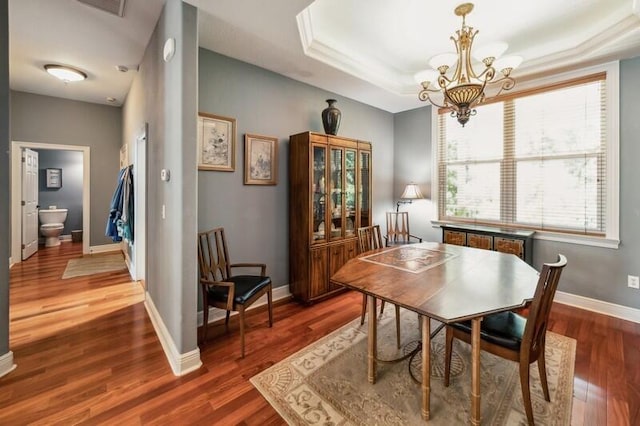 dining room with a tray ceiling, a chandelier, and dark hardwood / wood-style floors