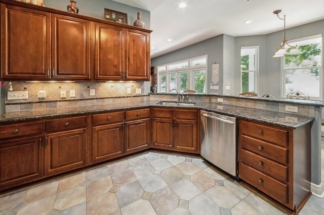 kitchen with hanging light fixtures, backsplash, dark stone counters, sink, and stainless steel dishwasher