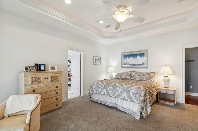 bedroom with ceiling fan, a tray ceiling, and a walk in closet