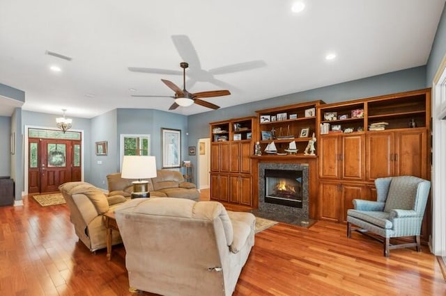 living room with a fireplace, light wood-type flooring, and ceiling fan