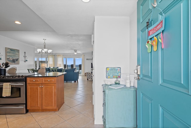 kitchen featuring light tile patterned floors, crown molding, ceiling fan with notable chandelier, kitchen peninsula, and stainless steel range with electric cooktop