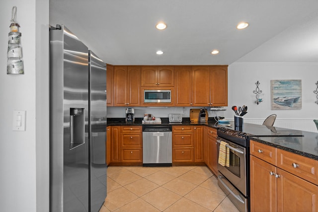 kitchen featuring crown molding, appliances with stainless steel finishes, dark stone counters, and light tile patterned flooring