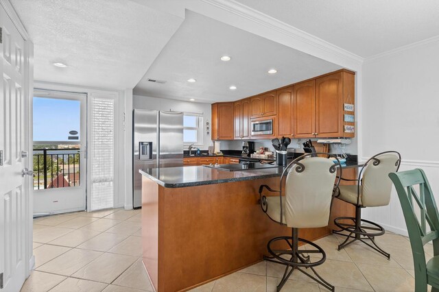 kitchen with appliances with stainless steel finishes, light tile patterned floors, kitchen peninsula, and a healthy amount of sunlight