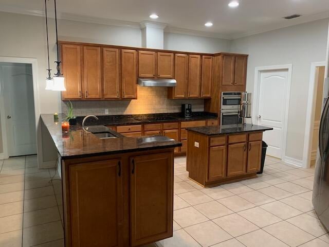 kitchen with stainless steel double oven, sink, light tile patterned floors, and decorative light fixtures