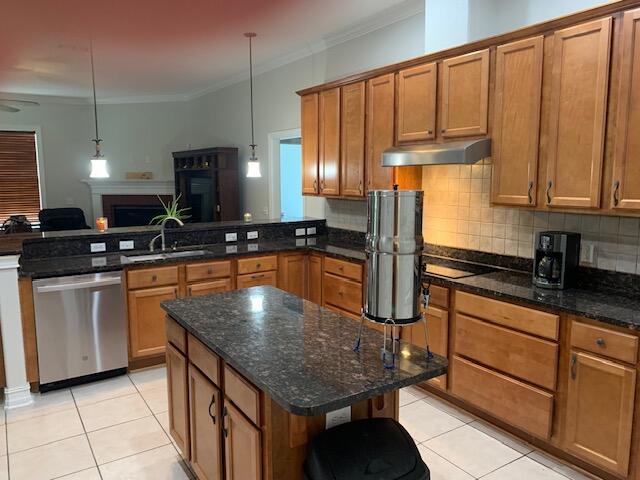 kitchen featuring dark stone counters, light tile patterned flooring, decorative light fixtures, crown molding, and stainless steel dishwasher