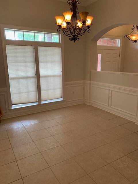 tiled empty room with a chandelier and plenty of natural light