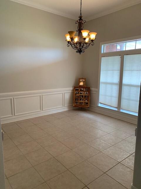 tiled spare room with crown molding and a chandelier