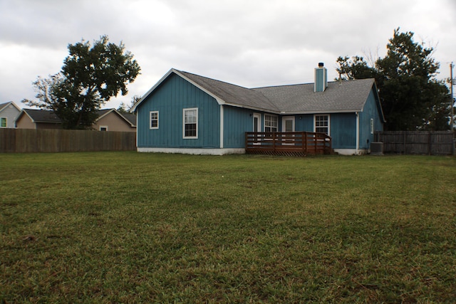 rear view of property featuring a lawn, central AC unit, and a deck