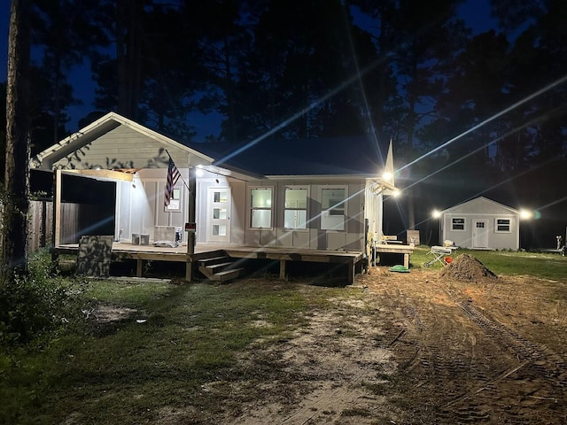 back house at twilight featuring an outbuilding and a wooden deck