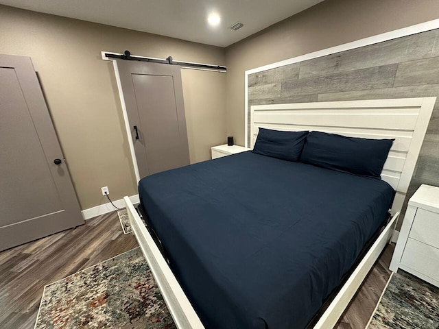 bedroom featuring dark hardwood / wood-style flooring and a barn door