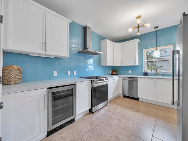 kitchen with wine cooler, appliances with stainless steel finishes, wall chimney exhaust hood, and white cabinetry