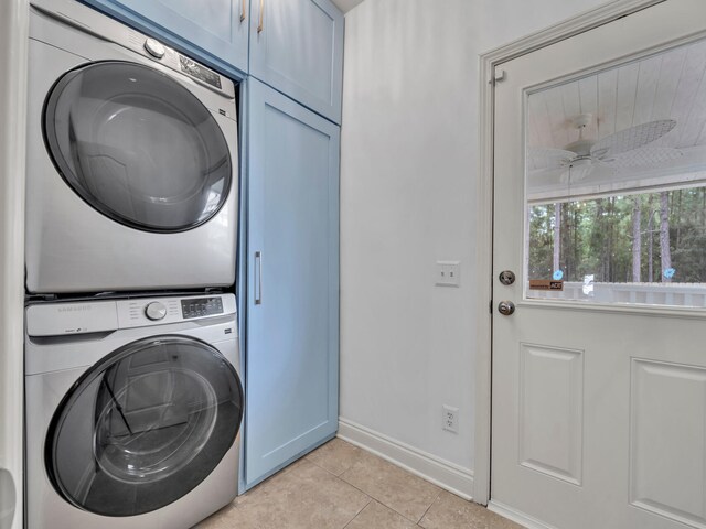 washroom featuring cabinets, ceiling fan, stacked washer / drying machine, and light tile patterned floors