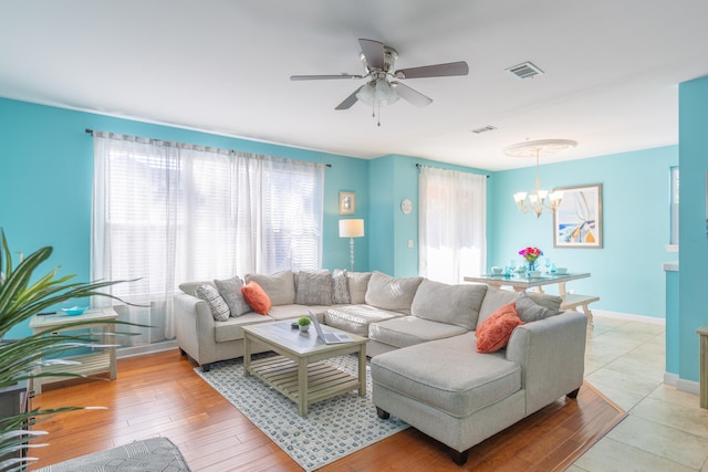 living room with ceiling fan with notable chandelier and light wood-type flooring